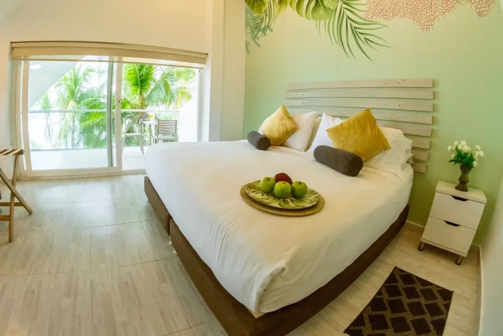 hermosa habitacion doble con un vibrante color verde adornada con un diseño de ramas que aporta un toque natural y fresco esta equipada con una cama doble y una mesa de noche