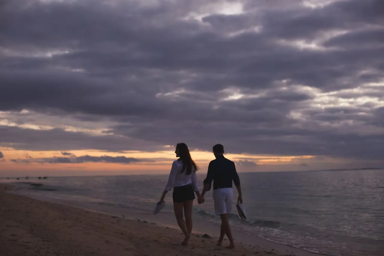 disfruta de un recorrido romántico por la playa en el anochecer.